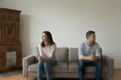 Ein unglückliches Paar sitzt abgewendet auf dem Sofa während einer Beziehungskrise oder Paarberatung